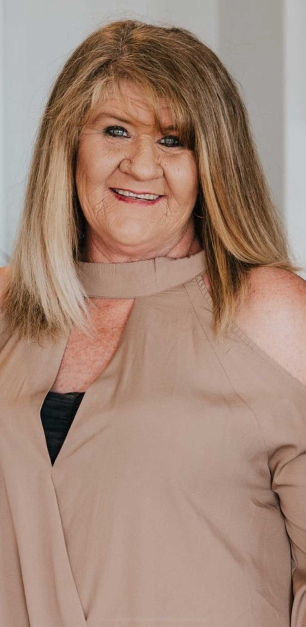 Woman with blonde hair in tan top