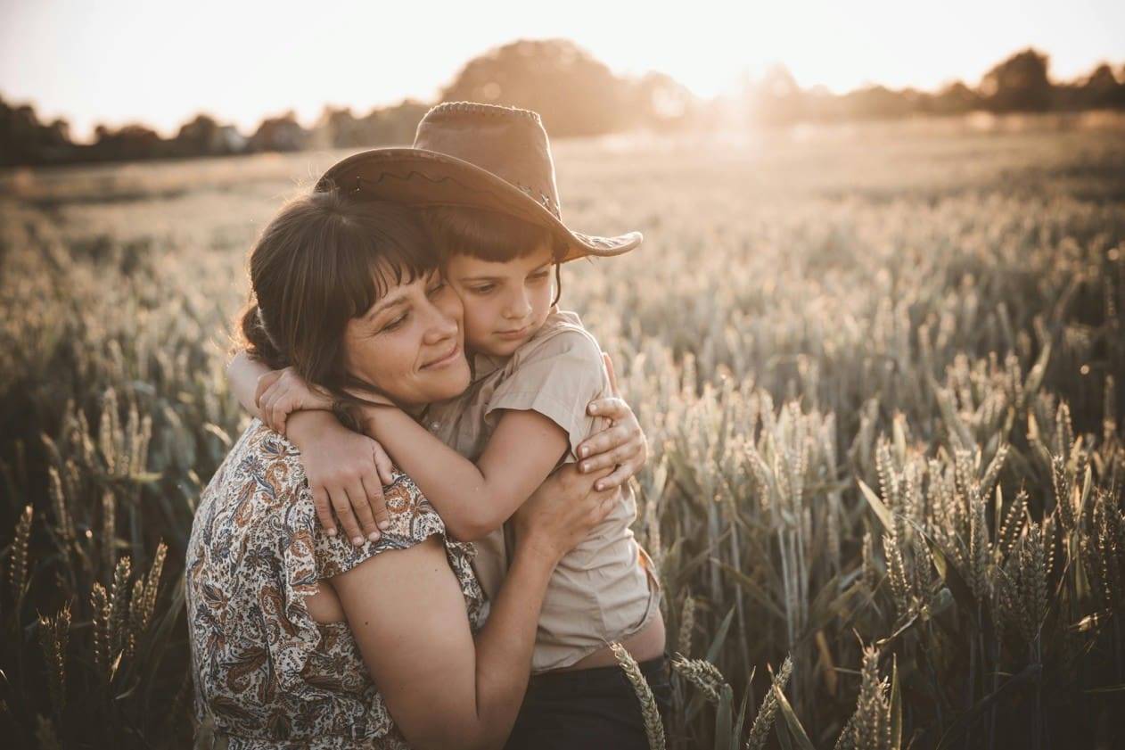 Adult and Child Embracing in a Sunlit Field Banner